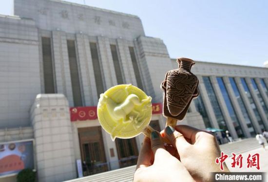 2021年7月30日，游客手拿“銅奔馬”“彩陶瓶”造型的雪糕，在甘肅省博物館前拍照打卡?！「哒?攝