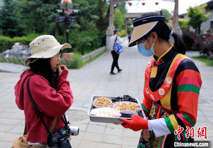 圖為身穿土族服飾的女性介紹當(dāng)?shù)靥厣〕?。　薛?攝