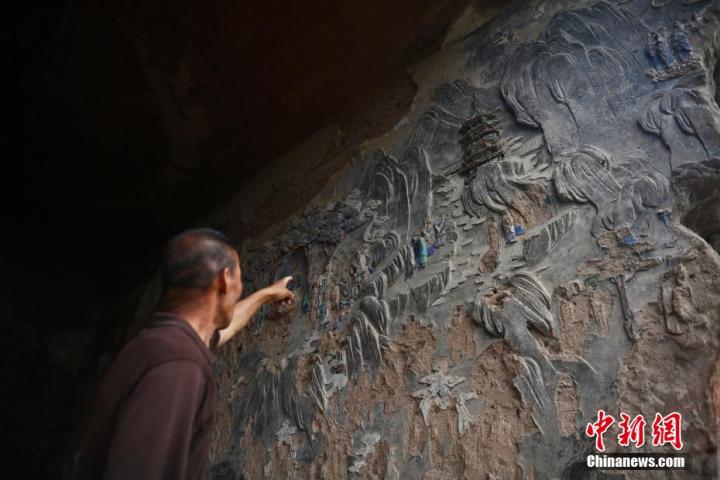 7月15日，甘肅省平?jīng)鍪袥艽h百里石窟長(zhǎng)廊羅漢洞石窟內(nèi)，該窟文保員郭建平介紹窟內(nèi)石刻彩繪壁畫(huà)。郭建平家中三代人曾自發(fā)保護(hù)羅漢洞石窟。羅漢洞石窟遺存40余個(gè)窟龕，以北魏至清代風(fēng)格為主。中新社記者 李亞龍 攝